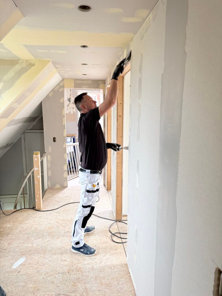 Maler i gang med malerarbejde i rum under renovering